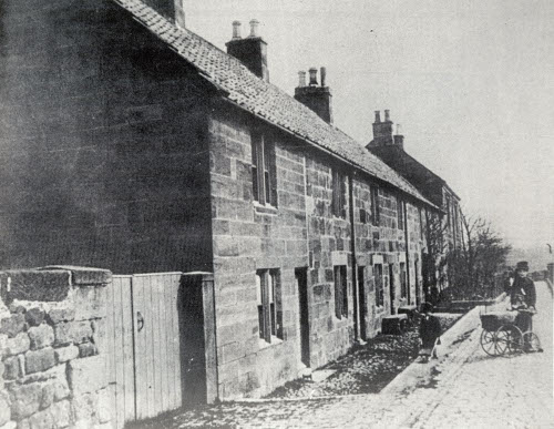 Guisborough Hospital before 1880. A black and white photograph of a row of cottages with children playing.