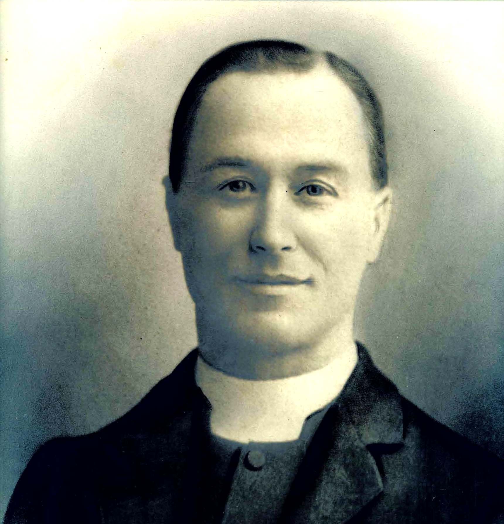 Black and white photograph of a white man in his middle years wearing a cleric's dog collar.
